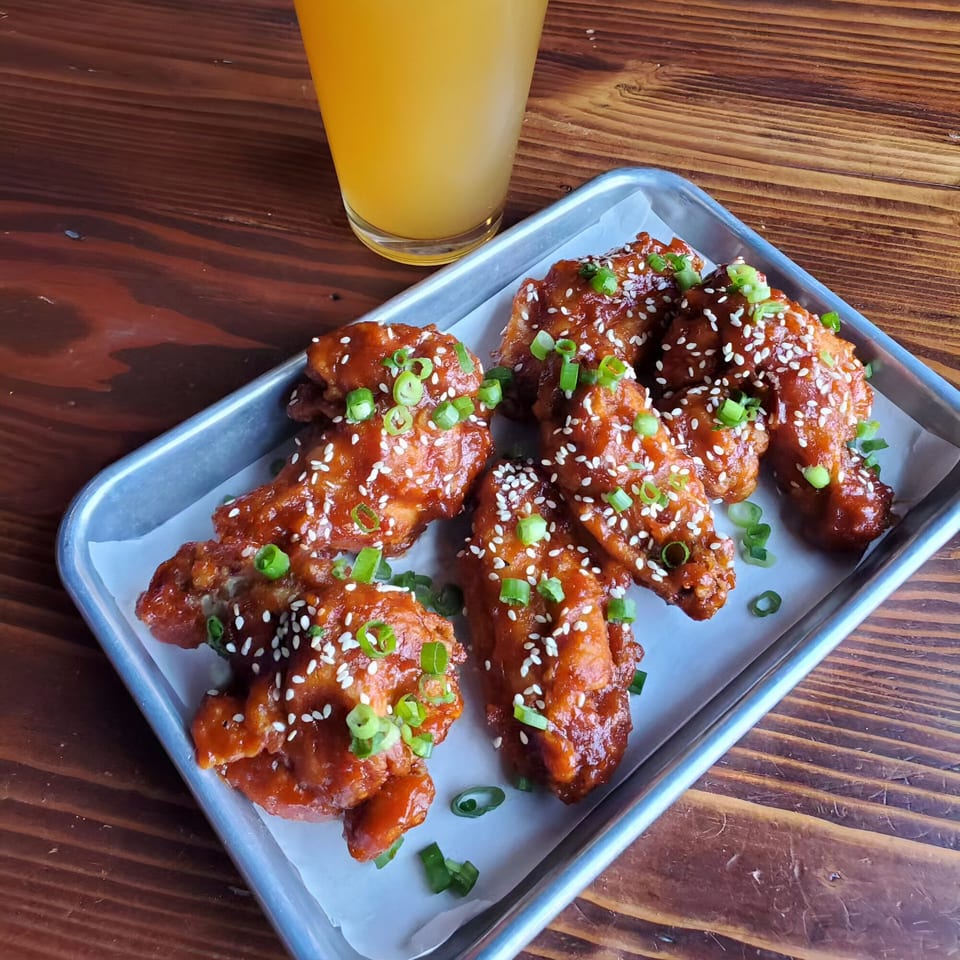 Chubby Bao House's Asian-style chicken wings, glazed with sauce, sesame seeds, and green onions.