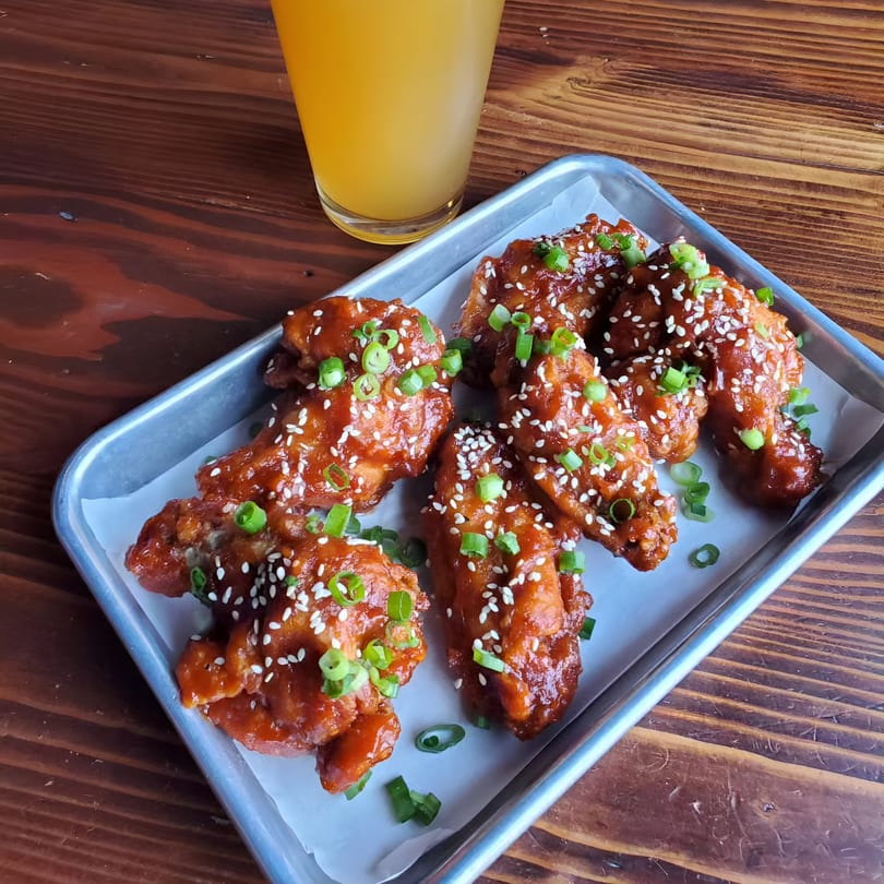 Chubby Bao House's Asian-style chicken wings, glazed with sauce, sesame seeds, and green onions.