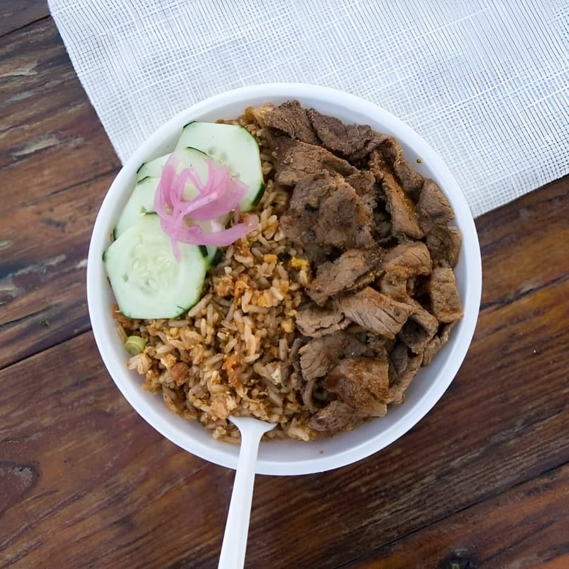 Chubby Bao House's beef and fried rice bowl with cucumber slices and pickled red onions.